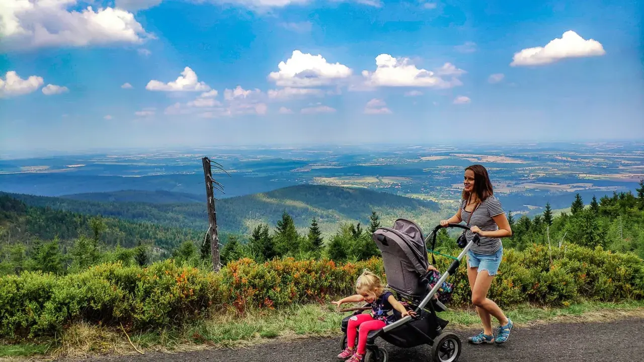 Mama z córką na spacerze, gdzie w góry z wózkiem. Piękny widok na dolinę i chmury.