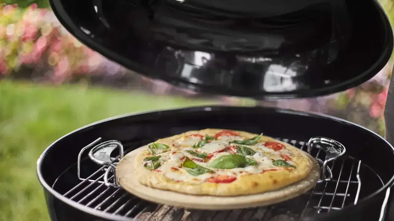 Pizza na kamieniu w grillu, gotowa do podania. Po pieczeniu czyszczenie kamienia do pizzy jest proste.