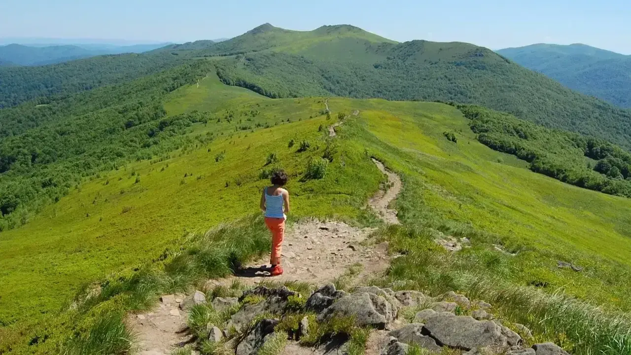 Dziewczynka na szlaku w zielonych górach. Gdzie w Tatry? Tu jest pięknie, zielono i słonecznie.