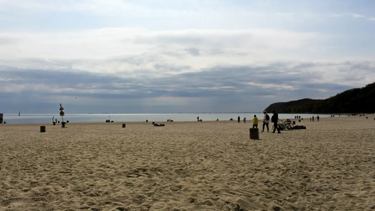 Plaża z ludźmi spacerującymi i odpoczywającymi. Idealny pomysł na weekend nad morzem.
