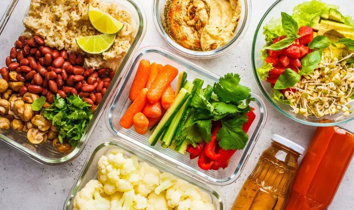 Gotowe jedzenie na biwak: ryż z fasolą i pieczarkami, warzywa pokrojone w słupki, kalafior, sałatka z kiełkami i pomidorami, hummus, soki.