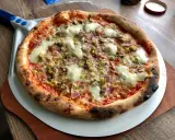 Pyszna pizza na kamieniu, z ciągnącym się serem, pieczarkami i oliwkami, gotowa do podania.