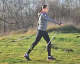 Kobieta w stroju sportowym ćwiczy nordic walking, używając kijków. Widać, jakie kije do nordic walking są lekkie i wygodne.