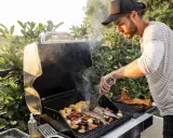 Mężczyzna grilluje ryby i warzywa na grillu gazowym, pokazując, jak działa grill gazowy.