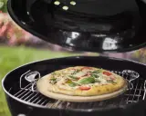 Pizza na kamieniu w grillu, gotowa do podania. Po pieczeniu czyszczenie kamienia do pizzy jest proste.