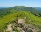 Dziewczynka na szlaku w zielonych górach. Gdzie w Tatry? Tu jest pięknie, zielono i słonecznie.