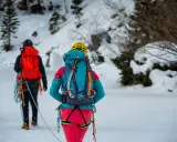 Dwóch alpinistów w zimowym krajobrazie, z plecakami i sprzętem, gotowych na wyprawę. To ich lista rzeczy na wyjazd w góry zimą.
