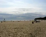 Plaża z ludźmi spacerującymi i odpoczywającymi. Idealny pomysł na weekend nad morzem.