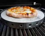 Pyszna pizza z grilla, z rumianym brzegiem i ciągnącym się serem, właśnie trafia na ruszt.