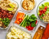 Gotowe jedzenie na biwak: ryż z fasolą i pieczarkami, warzywa pokrojone w słupki, kalafior, sałatka z kiełkami i pomidorami, hummus, soki.