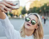Blondynka w okularach robi sobie selfie, pokazując, jak zrobić dobre selfie.