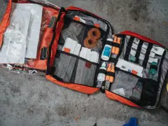 Rozłożona apteczka w góry, pełna plastrów, bandaży, płynów dezynfekujących i innych niezbędnych akcesoriów.