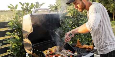 Mężczyzna grilluje ryby i warzywa na grillu gazowym, pokazując, jak działa grill gazowy.