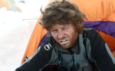 Zmęczony alpinista z białym pyłem na ustach, walczący z objawami choroby wysokościowej, w namiocie.