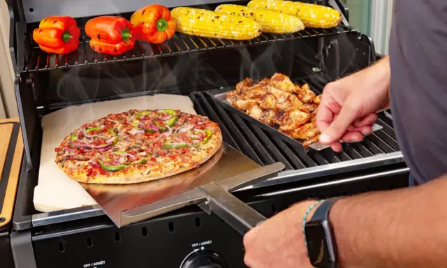 Pyszna pizza z grilla węglowego, obok kurczak i kukurydza.
