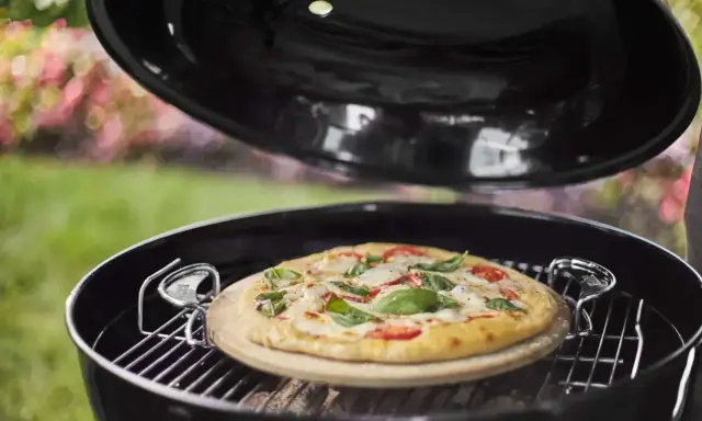 Pizza na kamieniu w grillu, gotowa do podania. Po pieczeniu czyszczenie kamienia do pizzy jest proste.