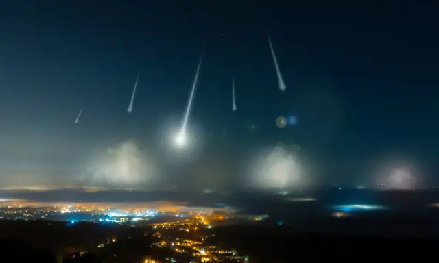 Noc perseidów nad miastem. Spadające gwiazdy przecinają ciemne niebo, oświetlając mgliste doliny i rozświetlone światłami zabudowania.