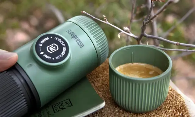 Zielona kawa w górach. Nanopresso i kubek z aromatycznym espresso na drewnianym pniu, wśród gałązek. Idealny towarzysz podróży.