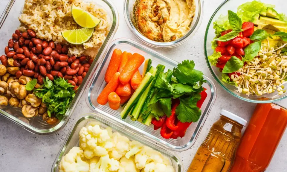 Gotowe jedzenie na biwak: ryż z fasolą i pieczarkami, warzywa pokrojone w słupki, kalafior, sałatka z kiełkami i pomidorami, hummus, soki.