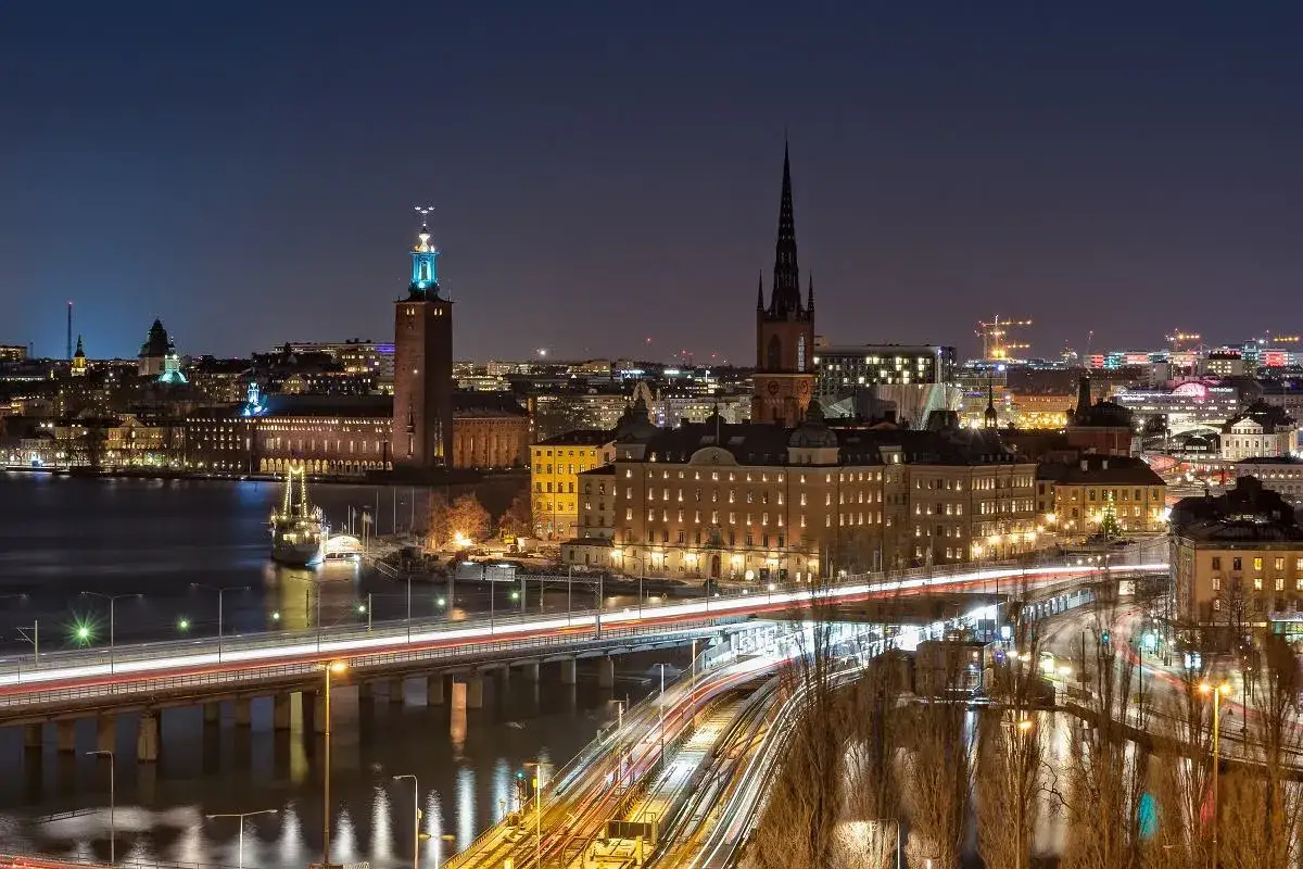 Sztokholm wycieczka na weekend: nocny widok na miasto z ratuszem, kościołem i mostami oświetlonymi światłami samochodów.