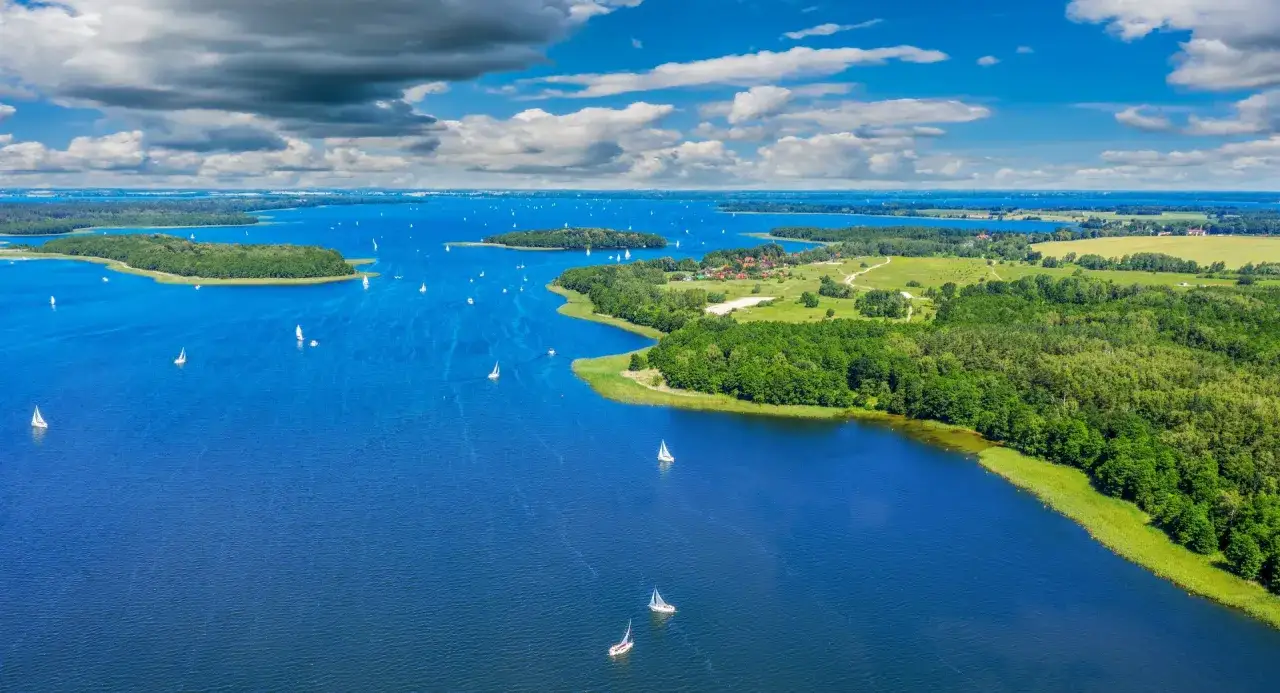 Mazury, gdzie warto pojechać w Polsce, to raj dla żeglarzy. Błękitne jeziora, zielone wyspy i liczne żaglówki tworzą malowniczy krajobraz.